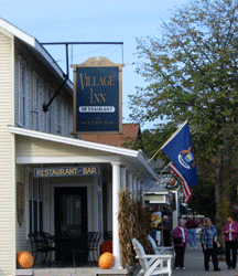 Some shoppers lingering on the sidewalk during the fall leaf peeper season in front of the Village Inn porch on St. Josephs Avenue in Suttons Bay